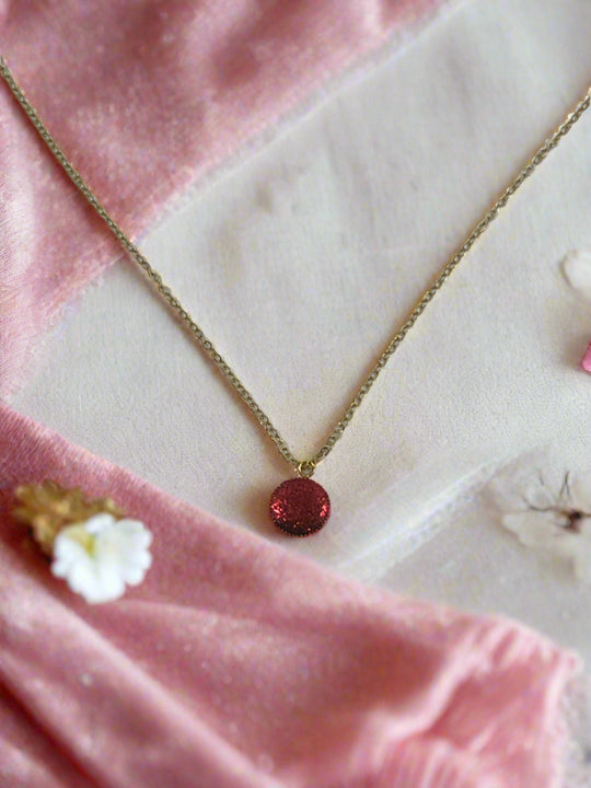 Ruby Crimson Shimmer Charm Necklace featuring a sparkling red charm on a delicate gold chain.