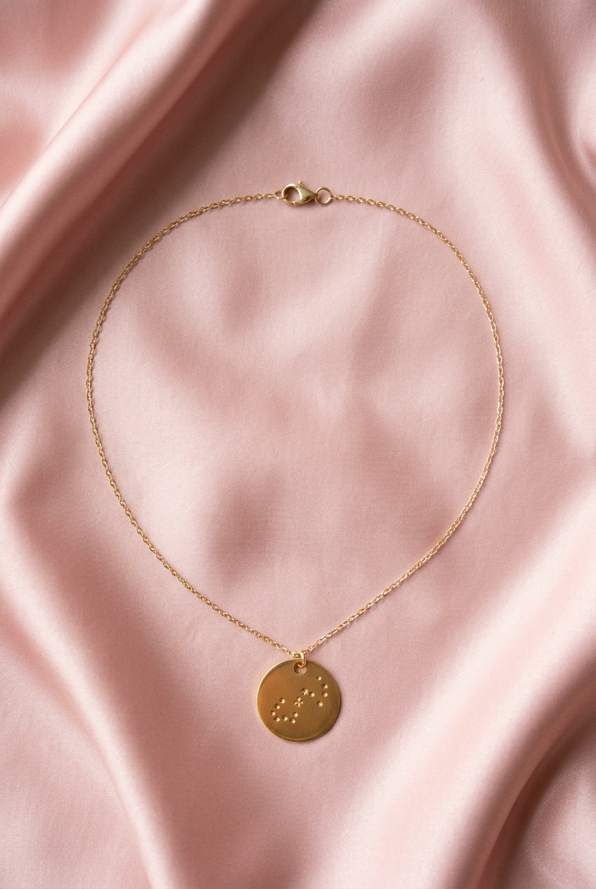 constellation disk necklace on a pink satin fabric background