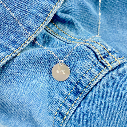 Silver Hand Stamped HOPE Necklace, our delicate gold disk necklace features a hand stamped "HOPE" message in simple script. Its minimalist design and it's delicate chain add a sweet, subtle touch making it a treasure to adore.