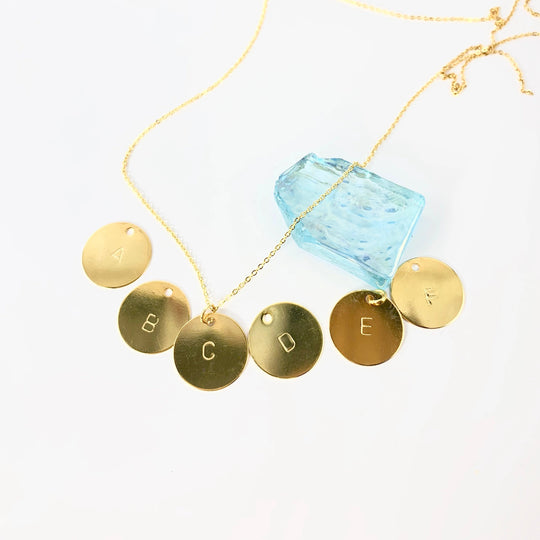 Gold Hand Stamped Initial Necklace, our dainty necklace features a 12mm gold disk hand-stamped with your chosen initial, with a delicate 14K gold-filled chain. Personal and sweet, a treasure to adore.