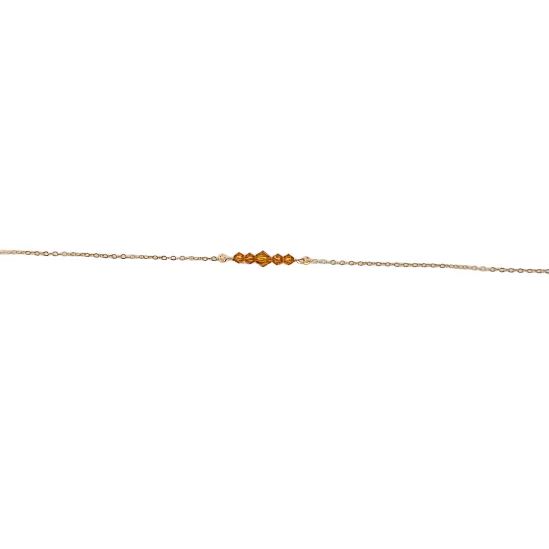 Topaz Orange Crystal Bar Necklace, this necklace has five tiny crystals on a 14k gold-filled chain. Petite and charming, it adds a subtle sparkle.