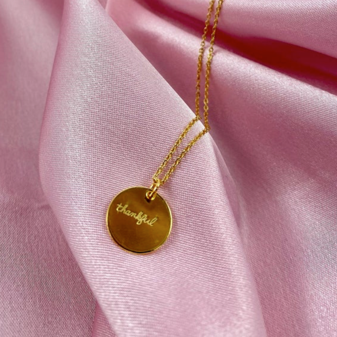 Hand Stamped Thankful Necklace, our delicate gold disk necklace features a hand stamped "thankful" message in simple script. Its minimalist design 