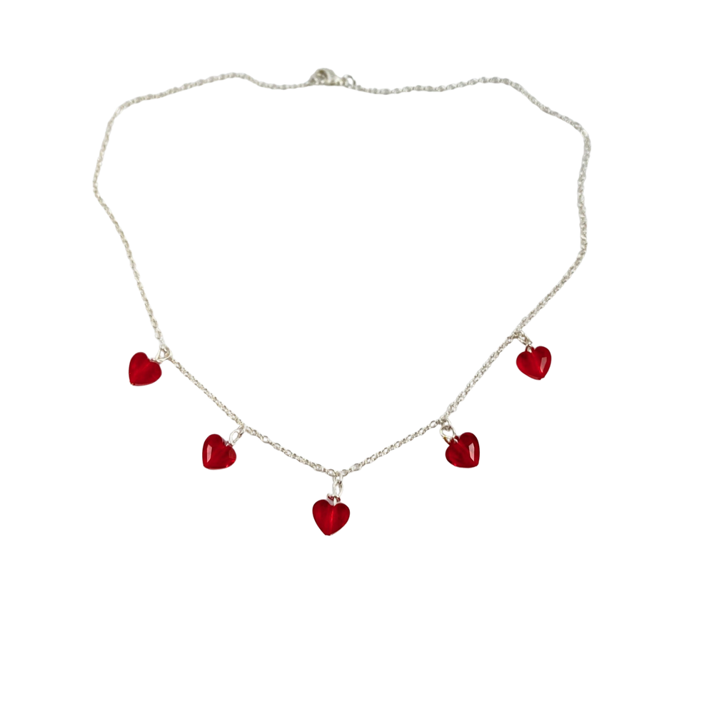 This Ruby Red Crystal Heart Necklace is irresistibly sweet and petite, featuring five tiny heart-shaped crystals wire wrapped on a sterling silver chain 