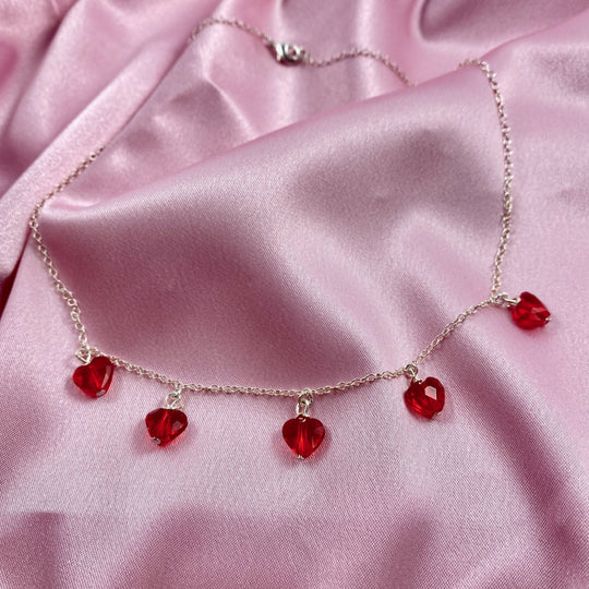 This Ruby Red Crystal Heart Necklace is irresistibly sweet and petite, featuring five tiny heart-shaped crystals wire wrapped on a sterling silver chain 